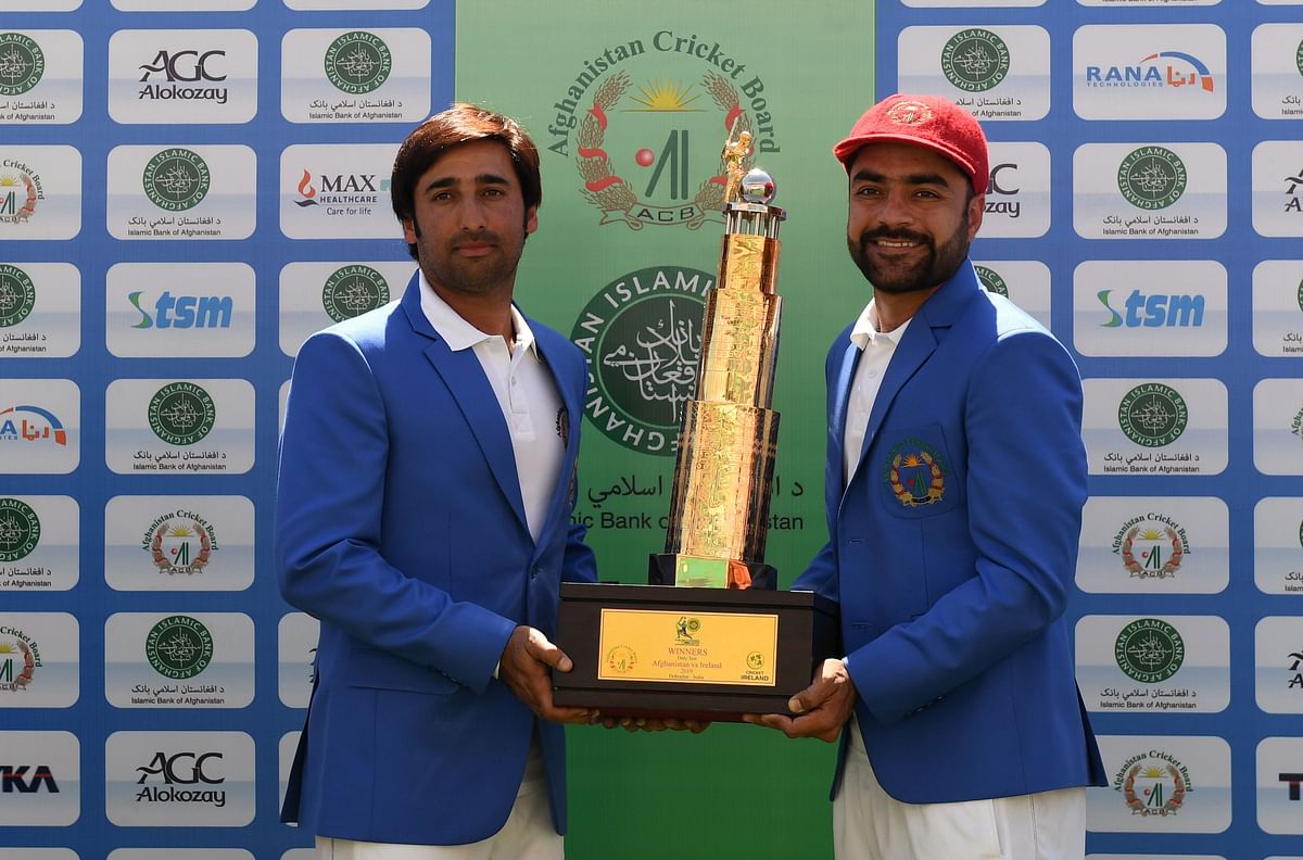 In this file photo taken on 18 March 2019, Afghanistan`s captain Asghar Afghan (L) and Rashid Khan pose with the trophy after winning the Test cricket match between Afghanistan and Ireland at the Rajiv Gandhi International Cricket Stadium in the northern Indian city of Dehradun. Photo: AFP