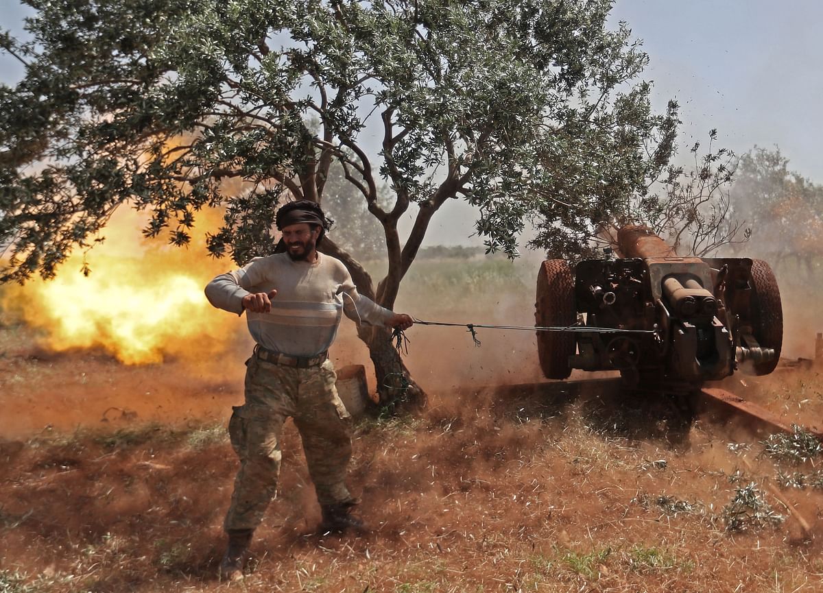 A Syrian fighter from the Turkish-backed National Liberation Front (NLF) fires a heavy artillery gun from the rebel-held Idlib province against against regime positions in the northern part of Hama province, on 22 May 2019. Photo: AFP
