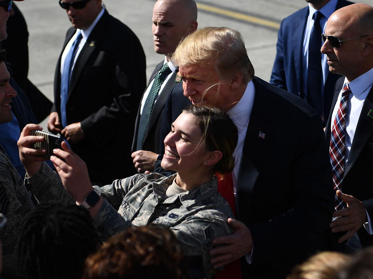 US president Donald Trump (C) poses for a selfie with a members of the military on the tarmac at Elmendorf Air Force Base in Anchorage, Alaska, during a refuel stop en route to Japan on 24 May. AFP File Photo