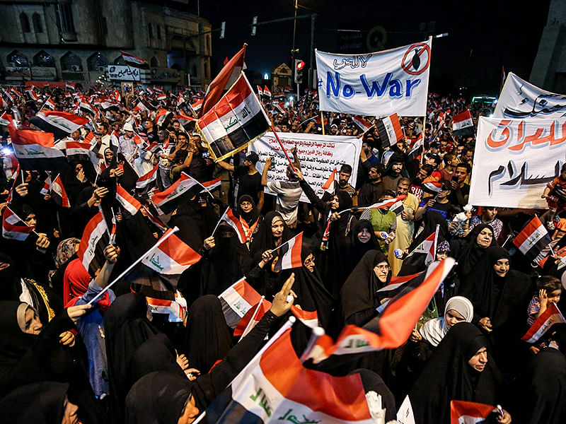 Iraqi followers of Shiite Muslim cleric Moqtada al-Sadr wave national flags and raise protest signs as they demonstrate in the capital Baghdad`s central Tahrir Square late on 24 May, against involvement in any conflict between Iran and the United States. AFP File Photo