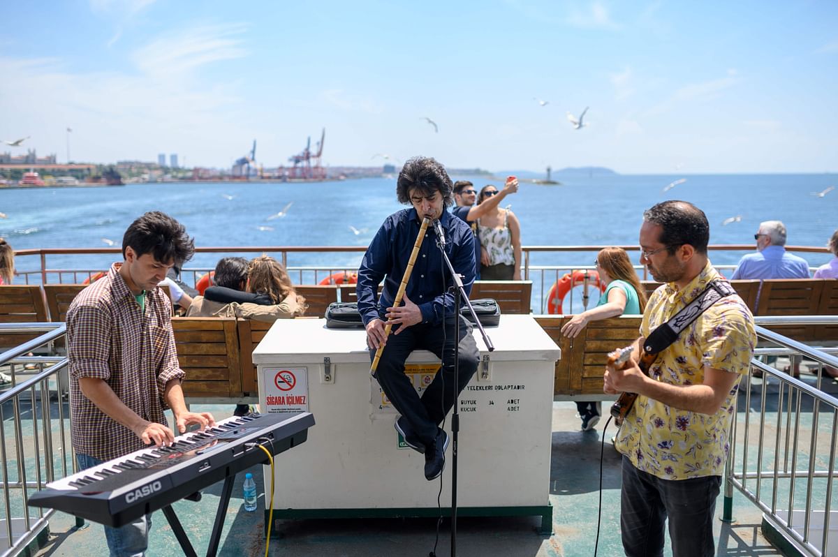 Musicians Oguzhan Erdem (C) plays ney, Eren Koc (L) keyboard and Zafer Saka(R) guitar during a ferry trip on the Bosphorus from Kadikoy to Eminonu, in Istanbul, on 16 May. Photo: AFP