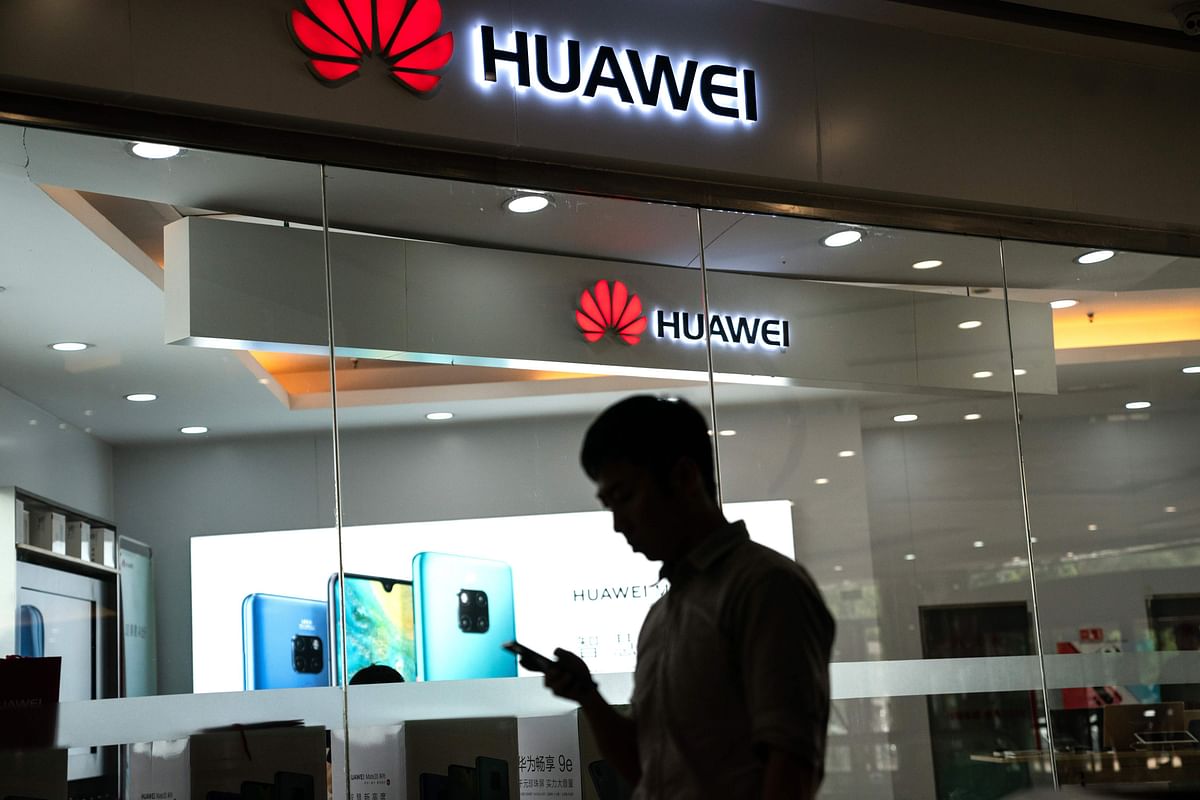 A man walks past a Huawei logo displayed at a retail store in Beijing on 23 May 2019. Photo: AFP