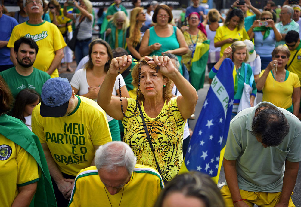 A supporter of Brazilian President Jair Bolsonaro prays as she takes part in a demonstration to shore up the ultraconservative government as it faces growing opposition, in Rio de Janeiro, while marches are planned across Brazil, on 26 May. Photo: Reuters