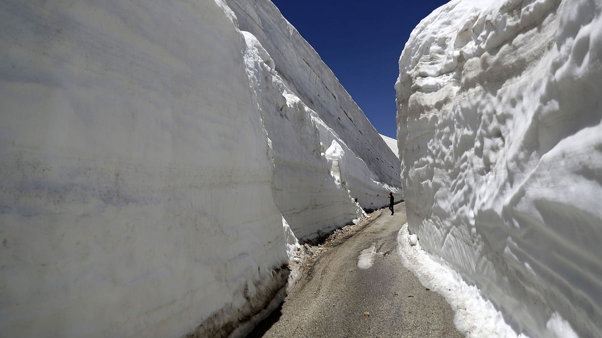 People take pictures on a road, surrounded by 10m walls of snow, on 28 May 2019, in the northern Lebanese village of Ainata al-Arz, 1620 m above sea level. The road has been recently serviced to allow for cars to access it. Photo: AFP
