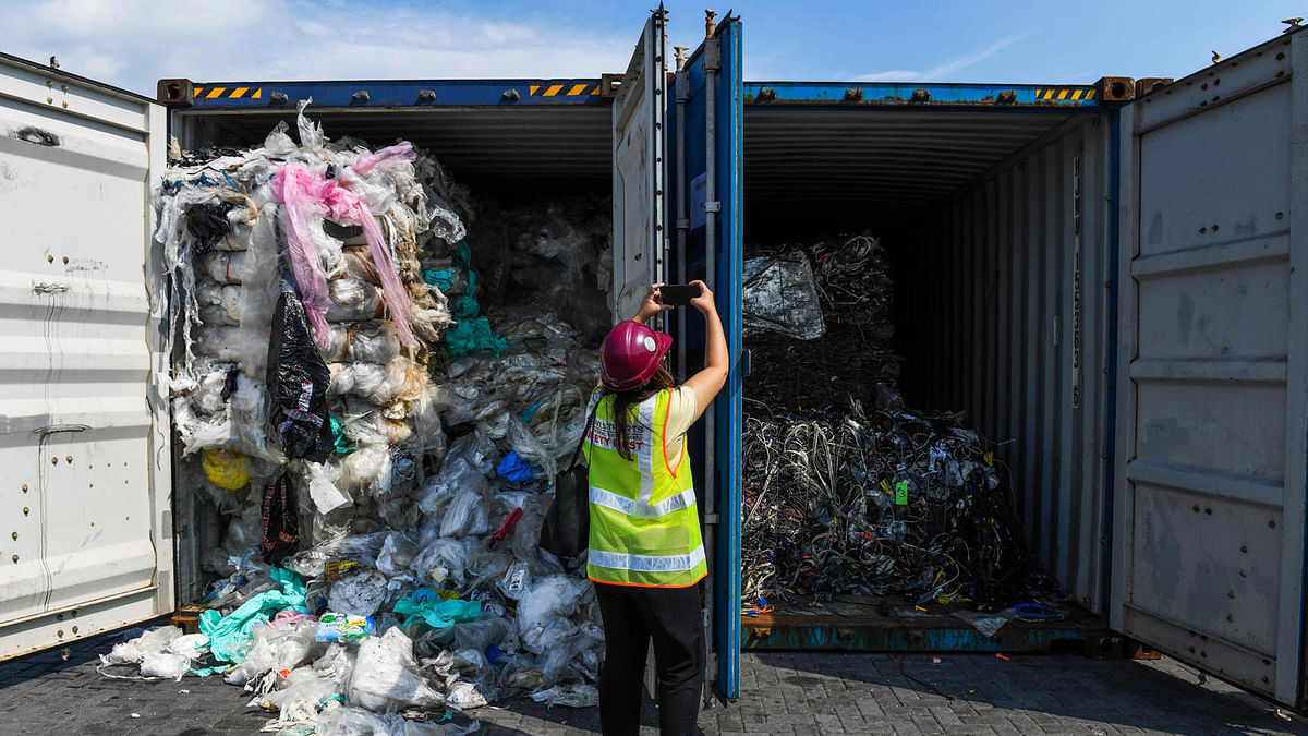 A member of the media takes pictures of containers filled with plastic waste before shipping back to the country of origin in Port Klang, west of Kuala Lumpur on 28 May 2019. Photo: AFP