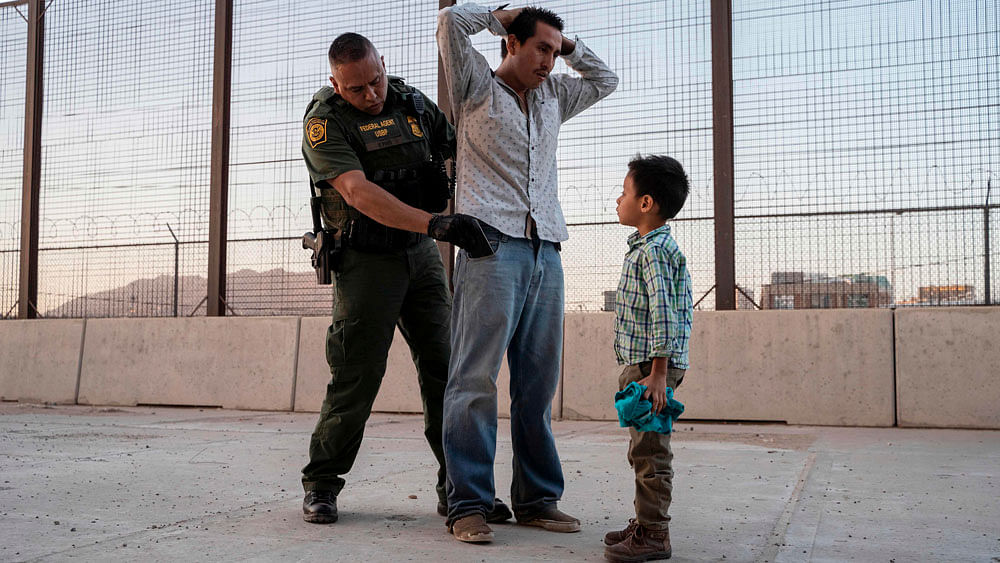 In this file photo taken on 16 May 2019, José, 27, with his son José Daniel, 6, is searched by US Customs and Border Protection Agent Frank Pino in El Paso, Texas. Photo: AFP