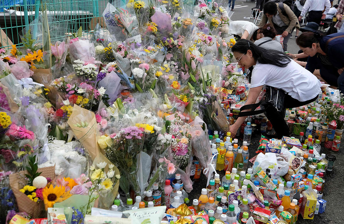 People pay their respects next to flower tributes at the crime scene where a man stabbed 19 people, including children, in Kawasaki on 29 May, 2019. Photo: AFP