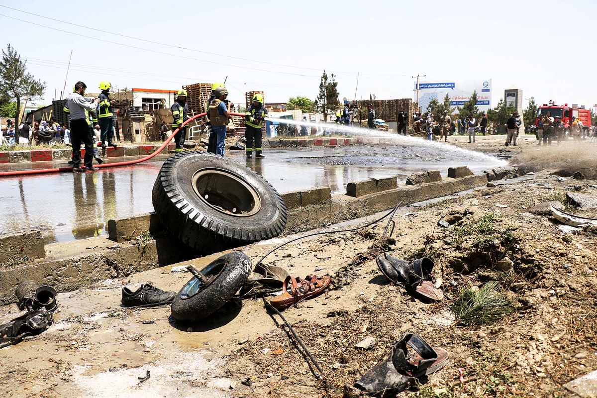 Afghan fire fighters wash a road with a pipe at the site of a car bomb attack that targeted a NATO convoy in Kabul on 31 May. Photo: AFP