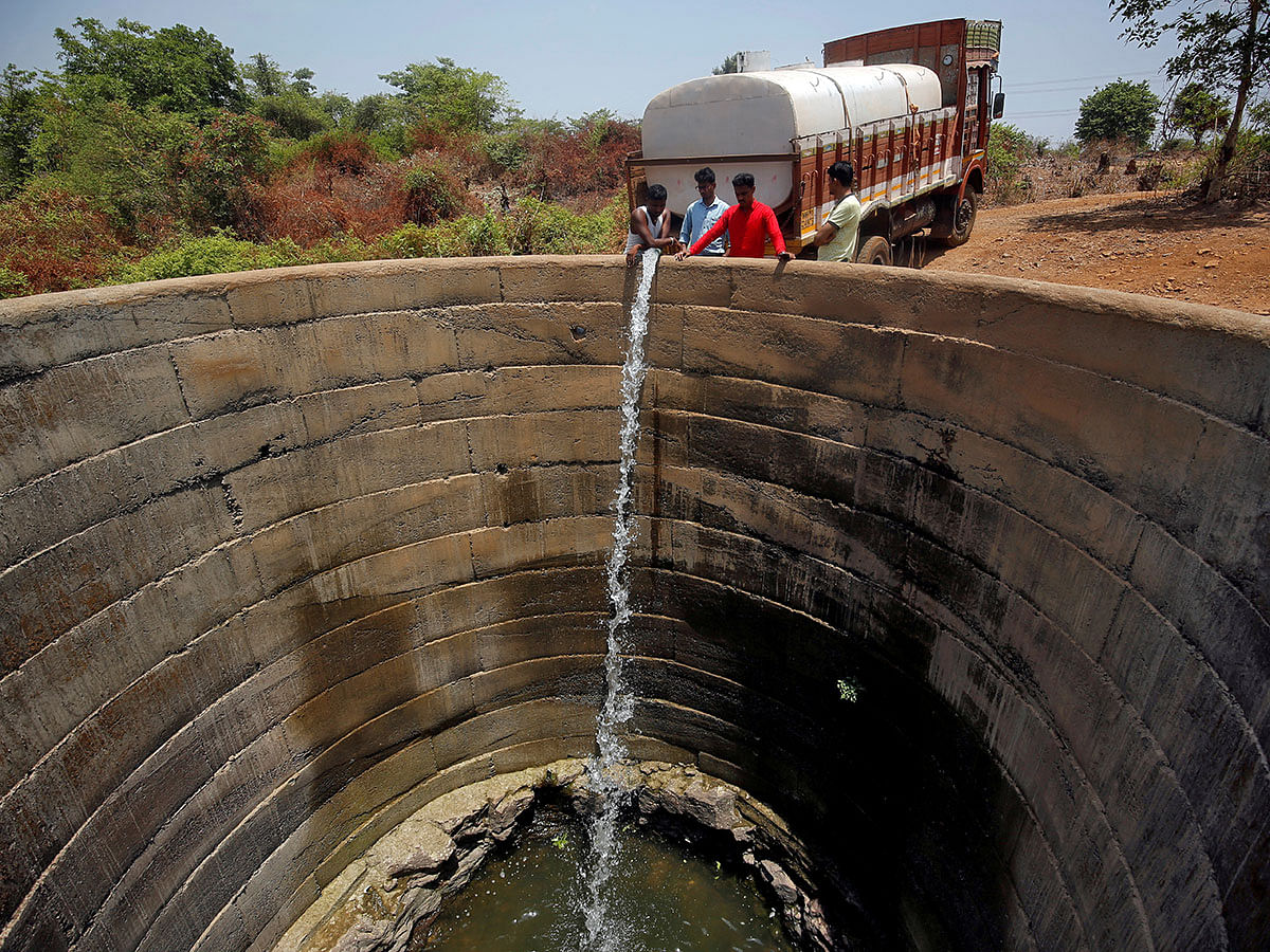 A dried-up well is refilled with water from a water tanker in Thane district. Photo: Reuters