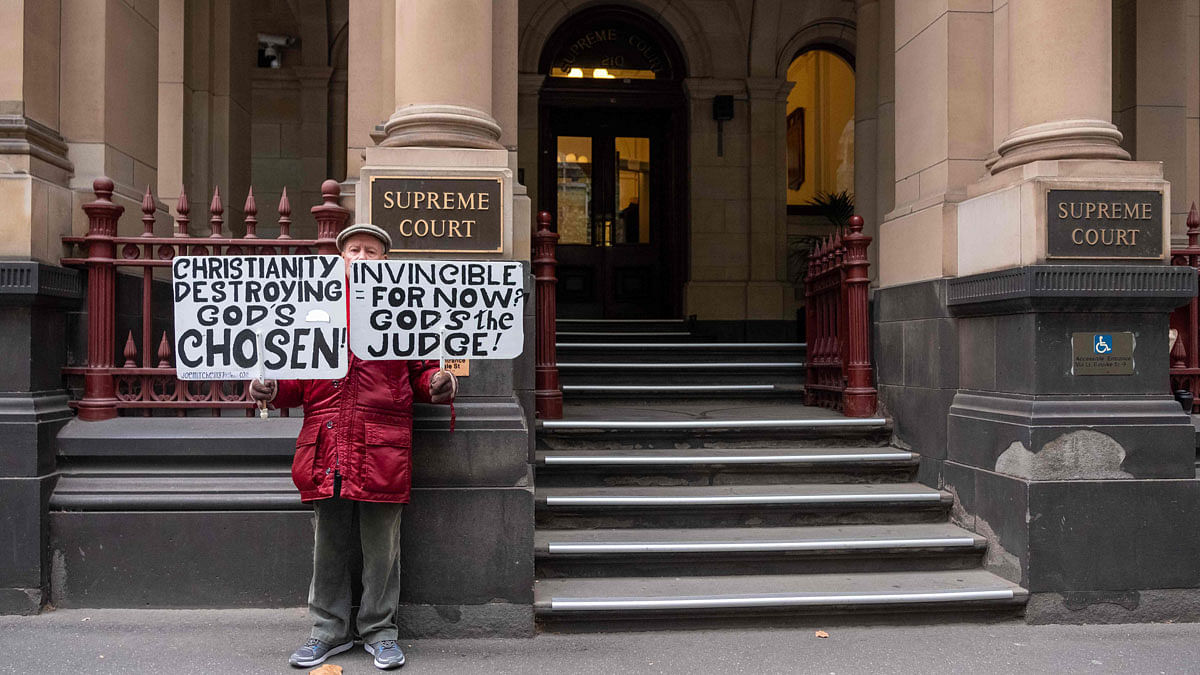 A protestor holding placards opposing the Catholic Church protests outside the Victorian Supreme court where Australian Cardinal George Pell has a hearing in Melbourne on 5 June. Photo: AFP