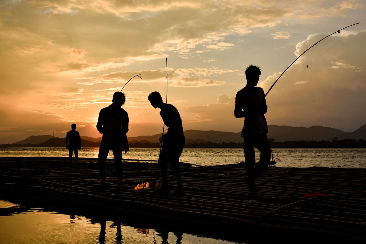 Indian children youths fish at sunset on floating bamboo along the Brahmaputra river in Guwahati in the Indian state of Assam on 8 June 2019. Photo: AFP