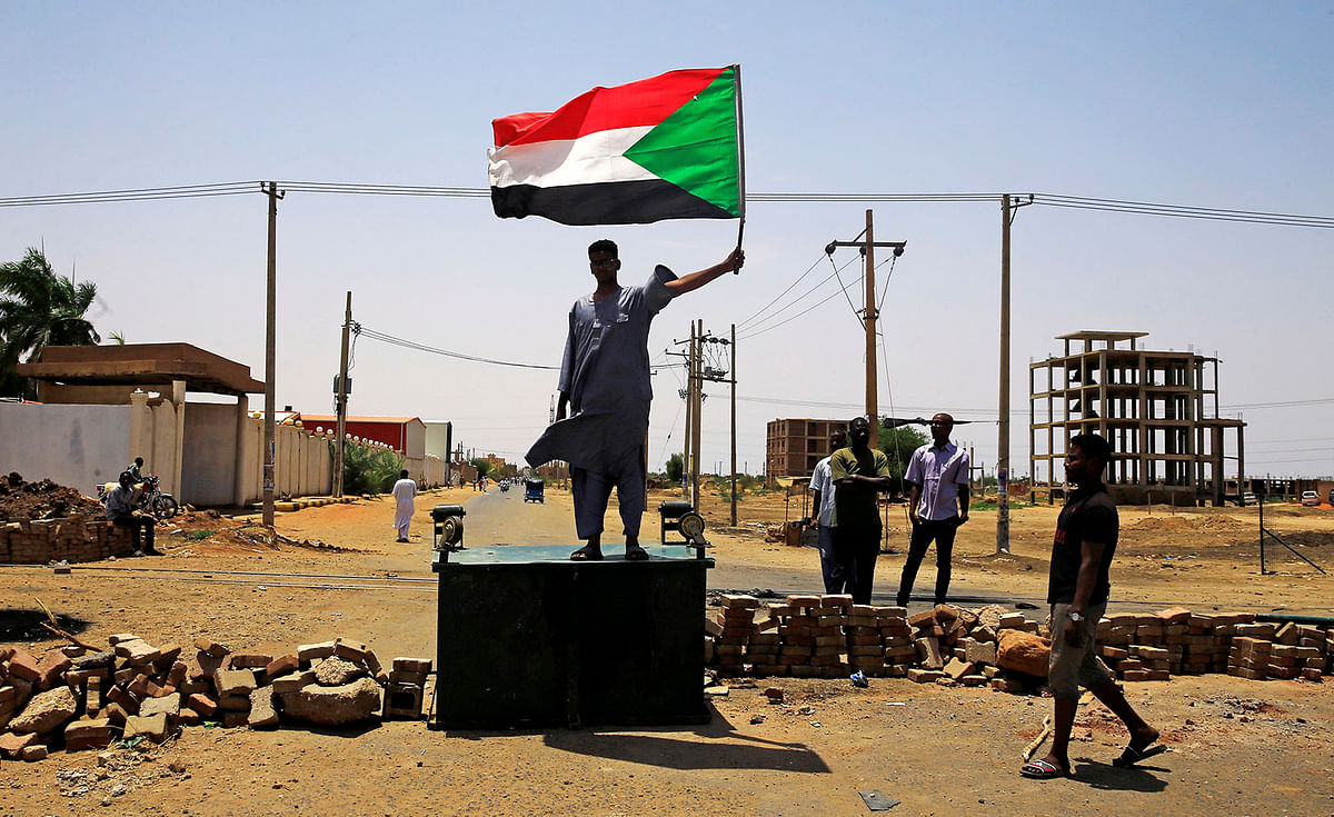 A Sudanese protester holds a national flag as he stands on a barricade along a street, demanding that the country`s Transitional Military Council hand over power to civilians, in Khartoum, Sudan on 5 June. Photo: AFP