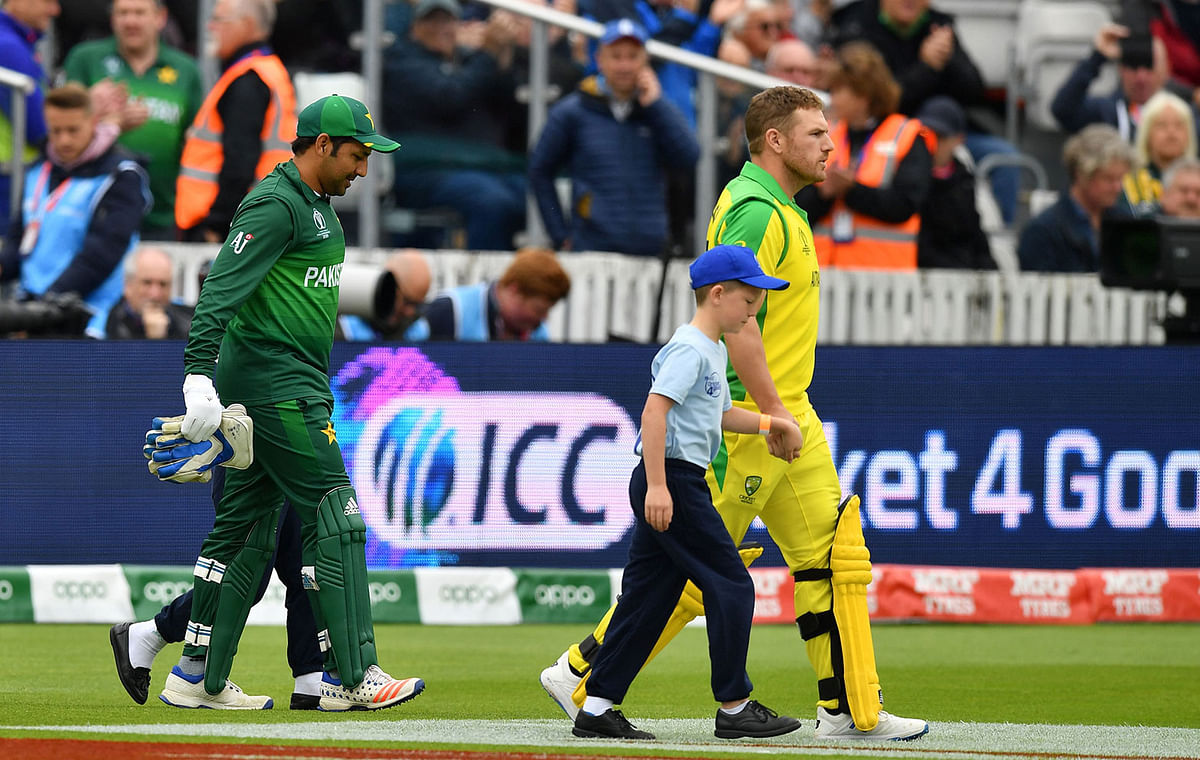 Pakistan`s captain Sarfaraz Ahmed (L) and Australia`s captain Aaron Finch lead their respective teams onto the field ahead of the 2019 Cricket World Cup group stage match at The County Ground in Taunton, southwest England, on 12 June 2019. Photo: AFP
