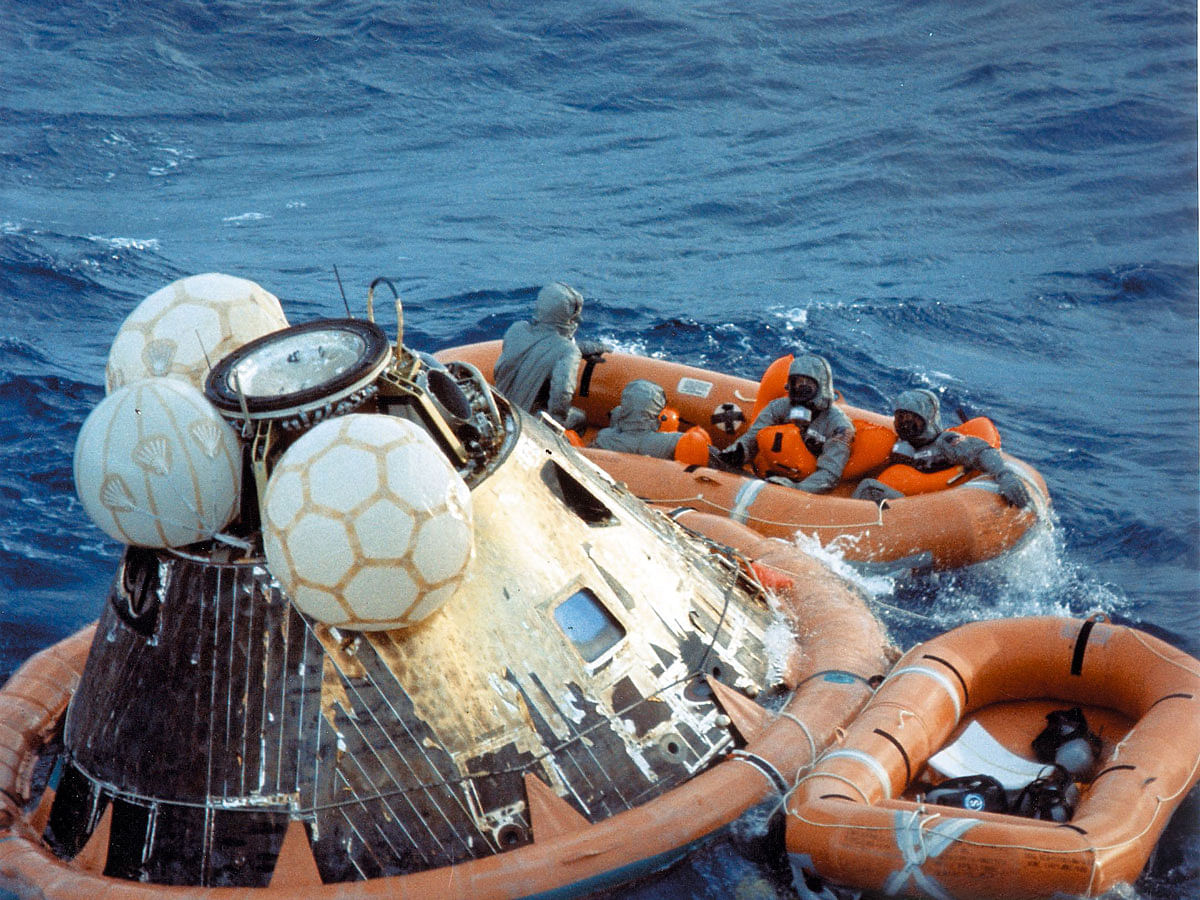 This 24 July 1969, photo obtained from NASA, shows US Navy pararescueman Lieutenant Clancey Hatleberg disinfecting Apollo 11 astronauts Neil Armstrong, Michael Collins, and Buzz Aldrin, wearing their quarantine suits in the life raft during recovery operations in the Pacific Ocean, after the successful completion of their lunar landing mission. Photo: AFP