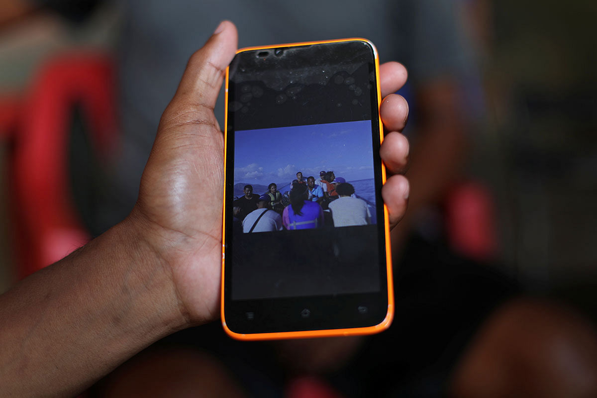 A friend of Maroly Bastardo, an eight months pregnant woman who, along with her children, her husband`s sister, uncle and father, disappeared in the Caribbean Sea after boarding a smuggler`s boat during an attempt to cross from Venezuela to Trinidad and Tobago, shows a picture of the boat that Bastardo and her family boarded, in Guiria, Venezuela on 24 May. Photo: Reuters