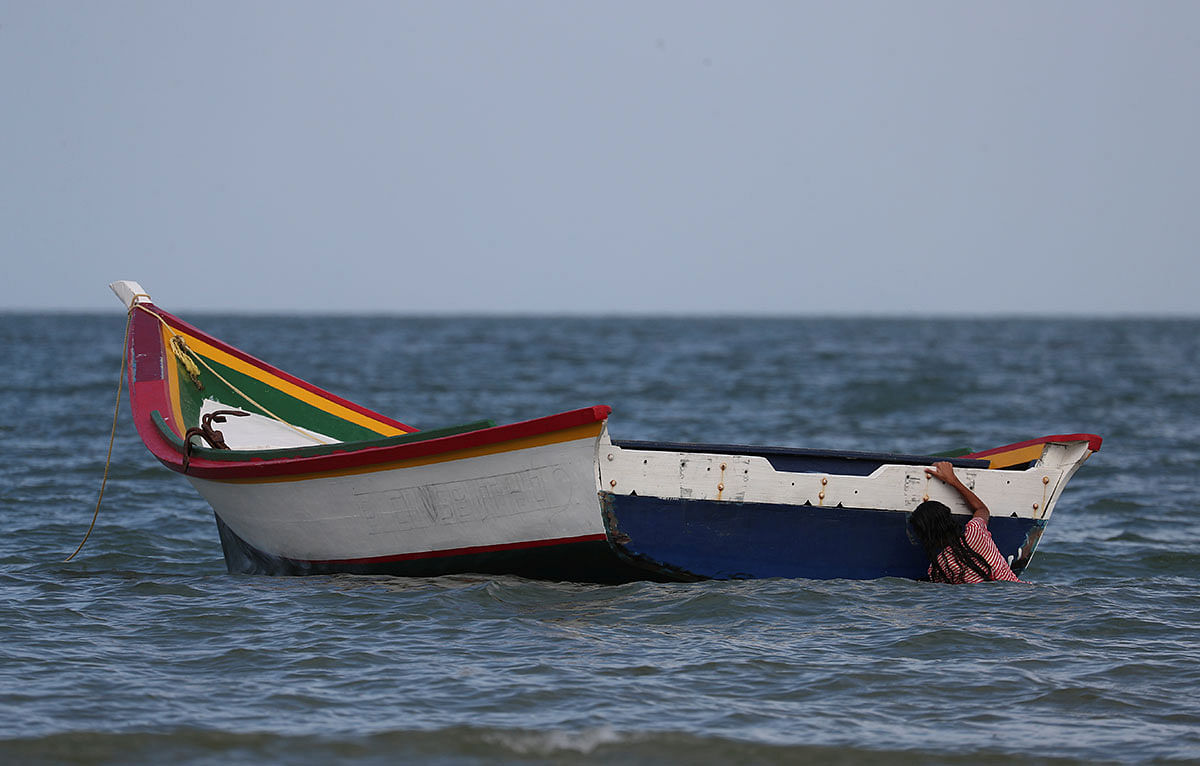 A girl holds a boat while playing at La Salina area from where Maroly Bastardo, an eight months pregnant woman, along with her children, her husband`s sister, uncle and father, boarded a smuggler`s boat and disappeared in the Caribbean Sea during an attempt to cross from Venezuela to Trinidad and Tobago, in Guiria, Venezuela on 24 May. Photo: Reuters