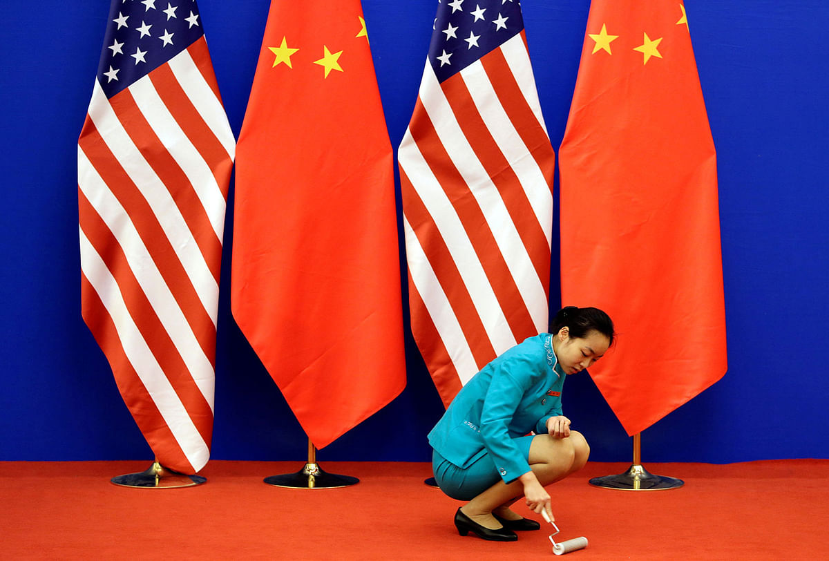 An attendent cleans the carpet next to US and Chinese national flags before a news conference for the 6th round of US-China Strategic and Economic Dialogue at the Great Hall of the People in Beijing, 10 July 2014. Reuters