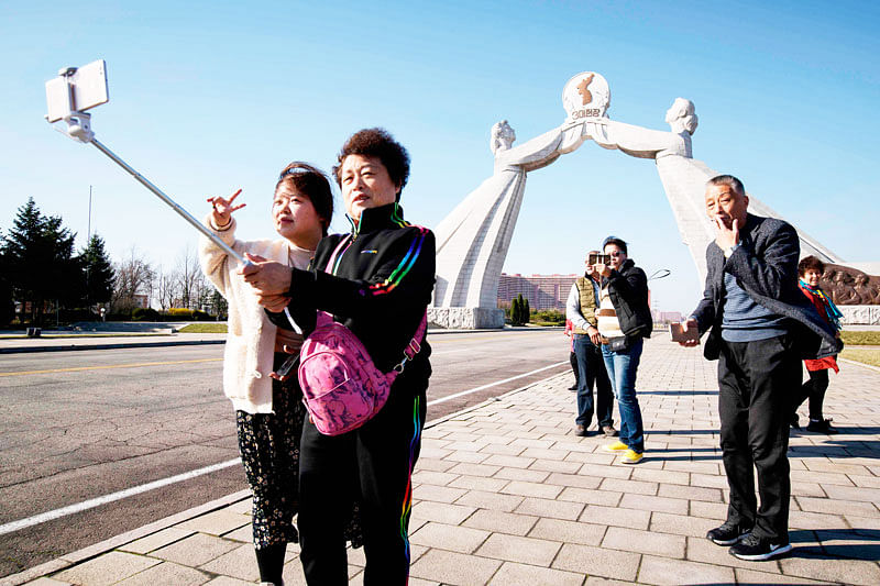 In a photo taken on 14 April 2019 tourists from China pose for photos before the Three Charters monument in Pyongyang. Ordinary Chinese pay travel companies around 2,500 yuan (360 US dollars) for a standard three-day trip to North Korea, arriving overland by train in Pyongyang to tour the capital`s highlights, from the Arch of Triumph to Kim Il Sung Square. Photo: AFP