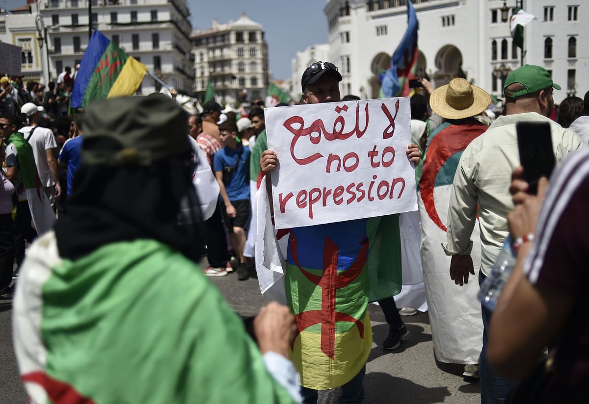 An Algerian man raises a placard as he takes part in a weekly demonstration in the capital Algiers on June 14, 2019. Demonstrations have continued since the ailing president stepped down, as protesters demand that regime insiders also exit as a precursor to independent institutions being set up. Photo: AFP
