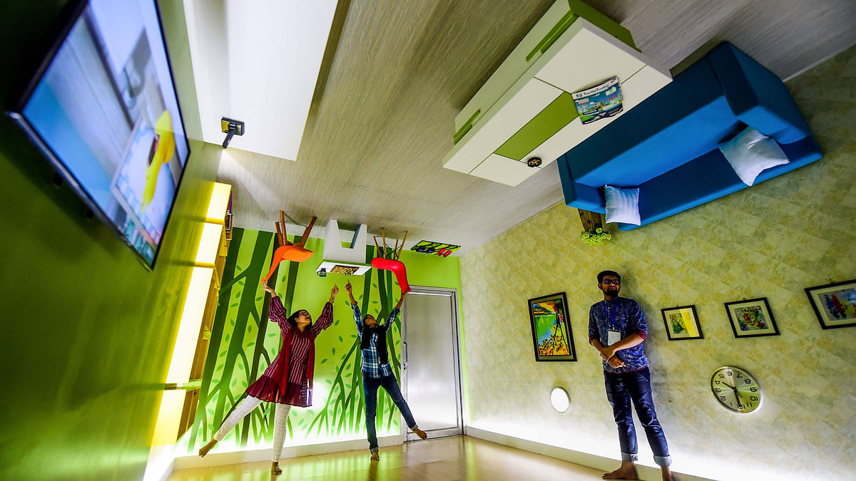 Visitors pose for a picture inside an upside-down cafeteria in Dhaka on 18 June 2019. Photo: AFP