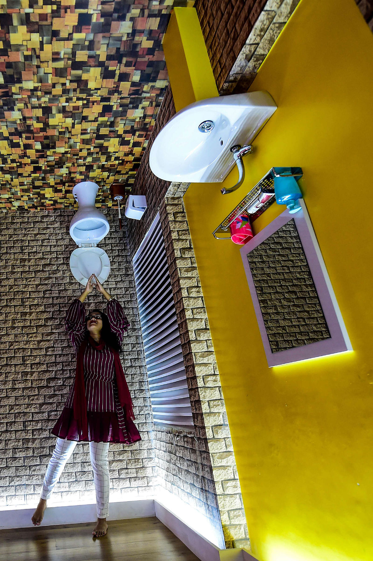 A visitor pose for a picture inside an upside-down cafeteria in Dhaka on 18 June 2019. Photo: AFP