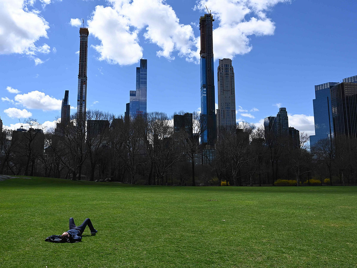 In this file photo taken on 10 April 2019, with the midtown skyline in the background, a man takes in the sun at the Sheep Meadow in Central Park in New York City. Photo: AFP