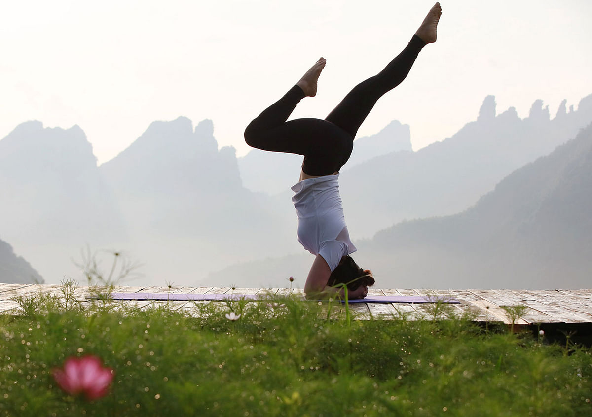 A yoga enthusiast practices yoga in the mountain village of Qiqi in Zhangjiajie, China`s central Hunan Province, on 20 June 2019. Photo: AFP