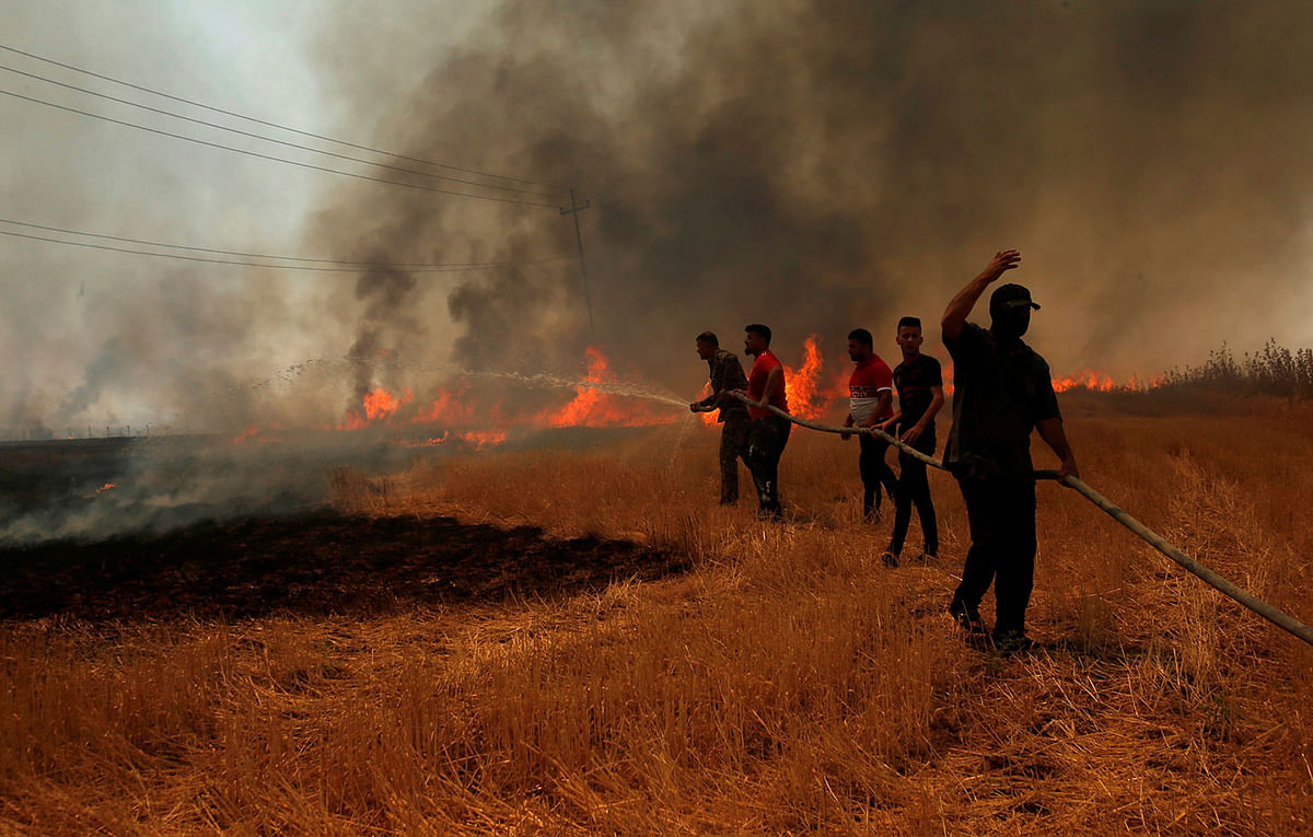 Iraqi farmers and other residents attempt to put out a fire that engulfed a wheat field in the northern town of Bashiqa, east of Mosul. Photo: Reuters