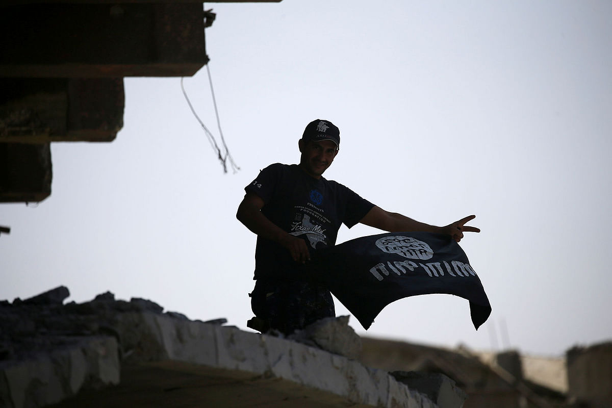 A member of the Iraqi security forces celebrates as he holds an Islamic State flag on top of a building destroyed in clashes in the Old City of Mosul, Iraq on 10 July 2017. Photo: Reuters