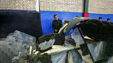 General Amir Ali Hajizadeh (C), Iran`s Head of the Revolutionary Guard`s aerospace division, looks at debris from a downed US drone reportedly recovered within Iran`s territorial waters and put on display by the Revolutionary Guard in the capital Tehran on 21 June 2019. Photo: AFP