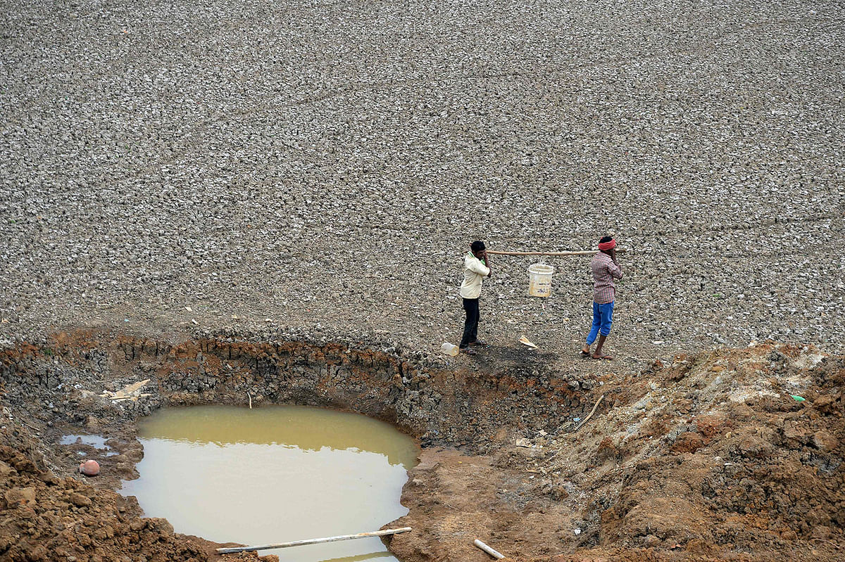 In this photo taken on 20 June Indian workers carry the last bit of water from a small pond in the dried-out Puzhal reservoir on the outskirts of Chennai. Photo: AFP