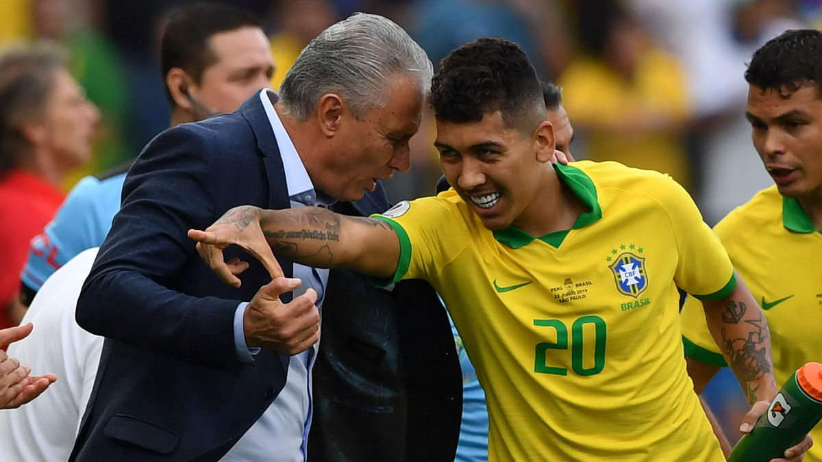Brazil`s Roberto Firmino celebrates with coach Tite (L) after scoring the team`s second goal against Peru during their Copa America football tournament group match at the Corinthians Arena in Sao Paulo, Brazil, on 22 June 2019. Photo: AFP