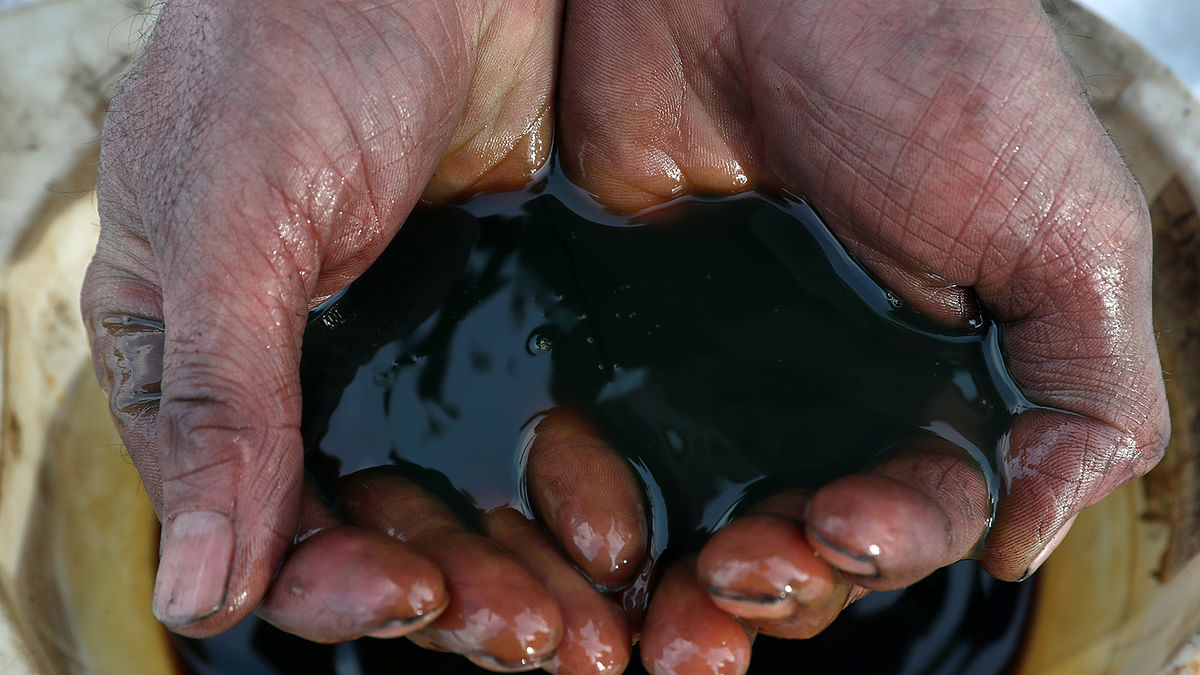 An employee holds a sample of crude oil. Reuters file photo