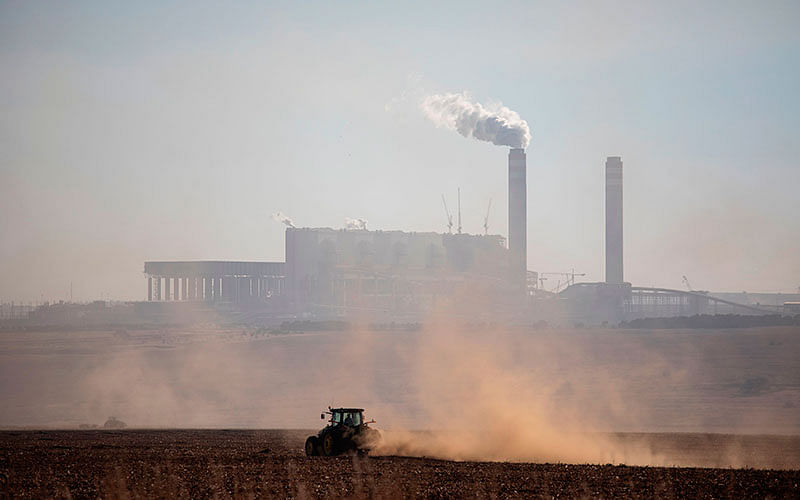 A farmer works with its tractor in front of the Kendal Power Station located in eMalahleni , part of the Highveld region turned over to mines and power plants, on 13 June 2019. Photo: AFP