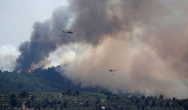 Helicopters drop water over a forest fire during a heatwave near Bovera, west of Tarragona, Spain, on 27 June 2019. Reuters File Photo