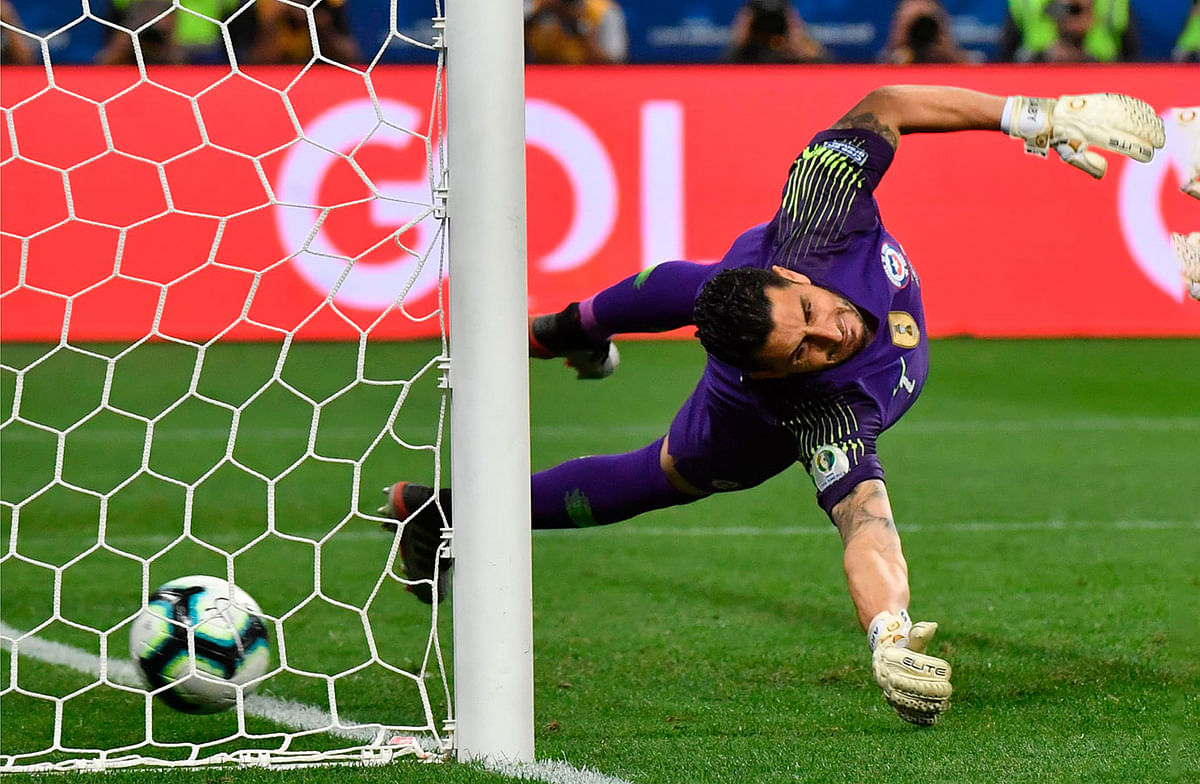 Chile`s goalkeeper Gabriel Arias stretches for the ball but cannot prevent Colombia`s Juan Guillermo Cuadrado from scoring during their penalty shoot-out after tying 0-0 during their Copa America football tournament quarter-final match at the Corinthians Arena in Sao Paulo, Brazil, on 28 June 2019. Photo: AFP