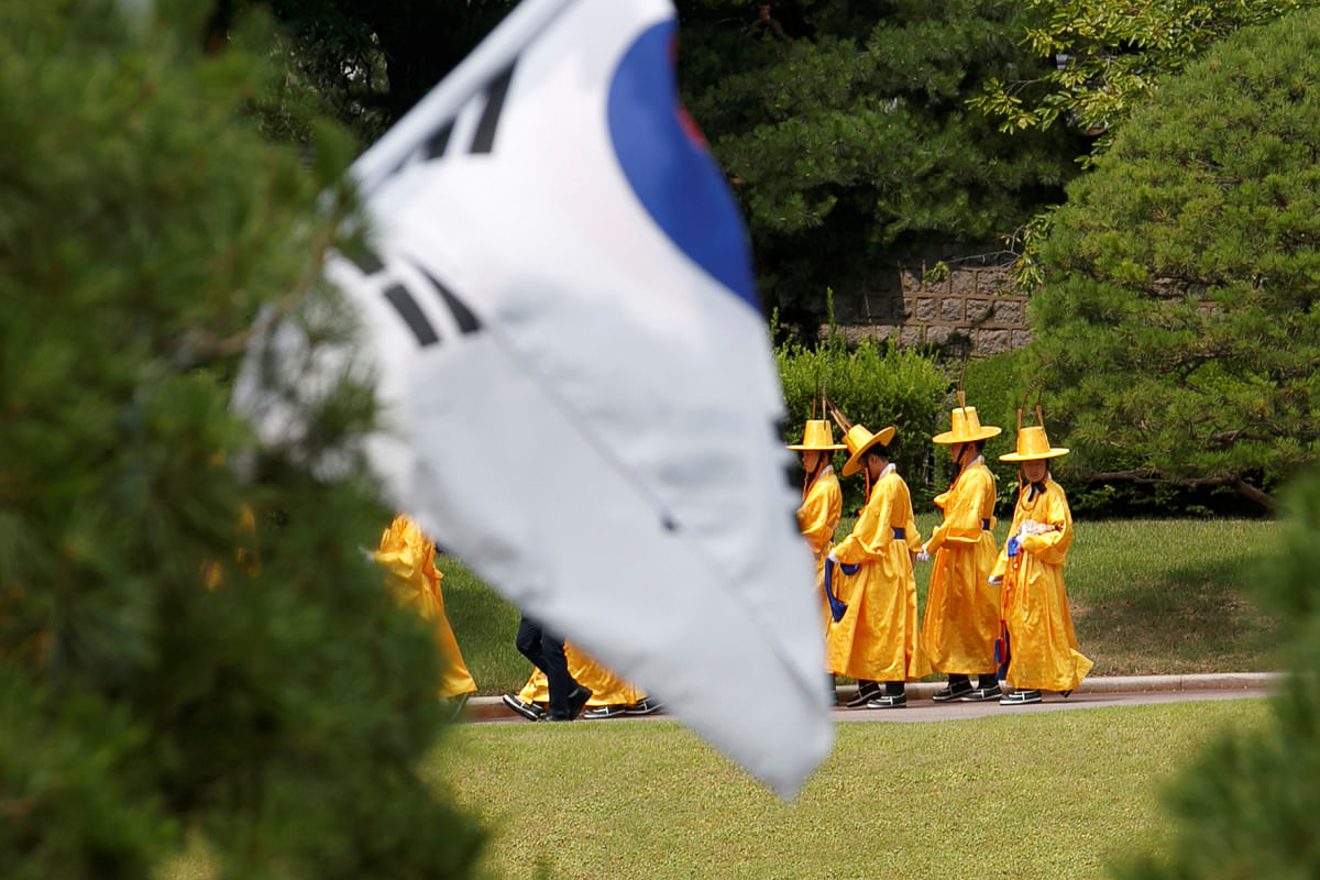 People in traditional dress walk past a South Korean flag in the foreground after the arrival of US president Donald Trump and Secretary of State Mike Pompeo to meet with South Korean President Moon Jae-in, at the Blue House, in Seoul, South Korea. Photo: Reuters