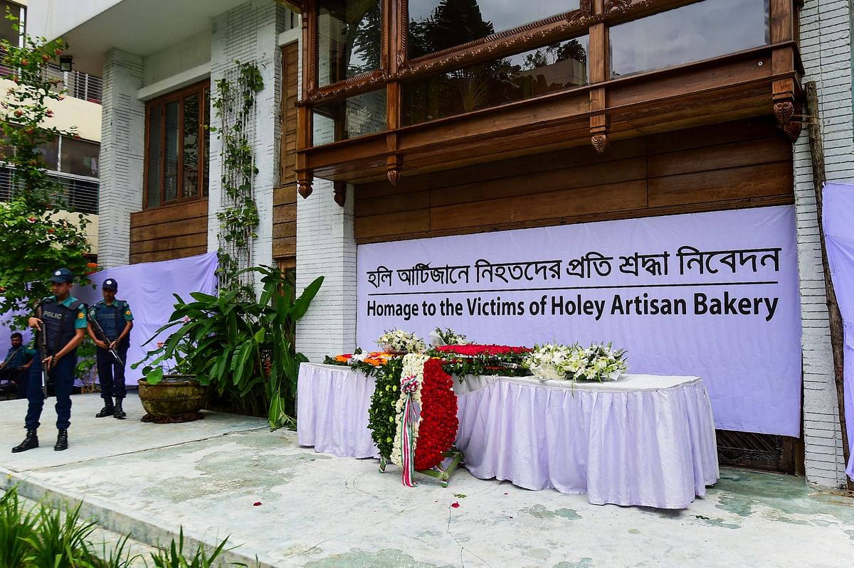 Police stand guard next to the tribute to victims of the Holey Artisan Bakery cafe siege to commemorate the third anniversary of the attack carried out by Islamist militants, in Dhaka on 1 July, 2019. Photo: AFP