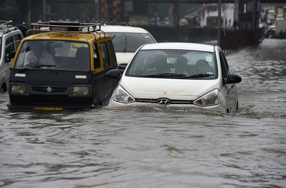 Vehicles drive along a flooded street after heavy rain showers in Mumbai on 1 July, 2019. Photo: AFP