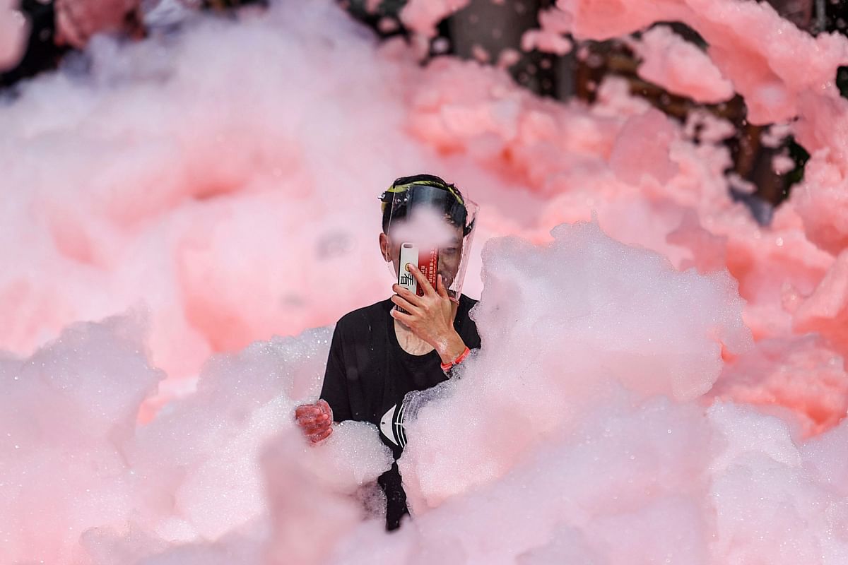 This photo taken on July 2, 2019 shows a participant taking photos in foam mixed with chili pepper water during an event, held to attract tourists to the region which is famous for spicy food, in Ningxiang county in China`s central Hunan province. - China OUT / AFP