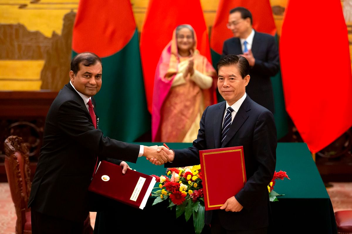 Chinese Commerce Minister Zhong Shan (R) shakes hands with a Bangladeshi delegate as Bangladesh`s prime minister Sheikh Hasina (back-L) and Chinese Premier Li Keqiang applaud during a signing ceremony at the Great Hall of the People in Beijing on 4 July 2019. Photo: AFP