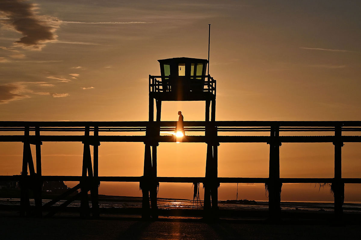 A man walks on the pier at sunset in Luc-sur-mer (Normandy), northwestern France, on 5 July 2019. Photo: AFP