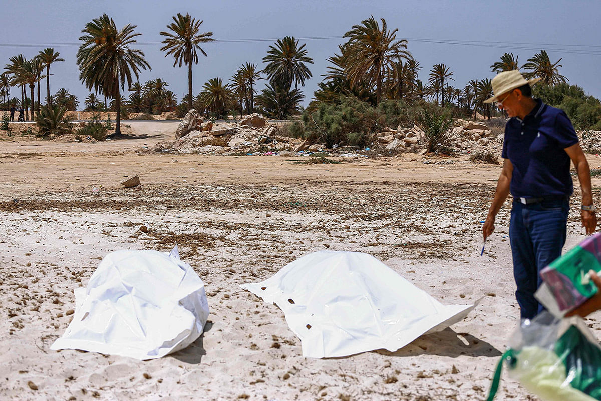A representative of the Tunisian Red Crescent association checks bodies recovered from a boat carrying 86 migrants that capsized off the Tunisian coast while crossing the Mediterranean from Libya to Italy, as they lie on a beach in Aghir in Tunisia`s southern island of Djerba on 6 July 2019. Photo: AFP