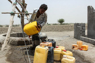 A boy displaced from the eastern Yemeni district of Durahemi pours water drawn from a well into jerry cans near the Red Sea port city of Hodeida on 9 July 2019. Photo: AFP