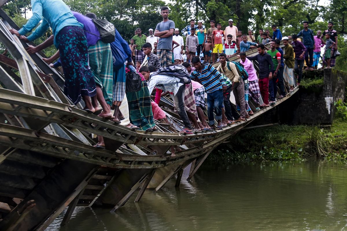 Bangladeshi pedestrians cross a broken bailey bridge in Sylhet on 7 July, 2019. While heavy vehicle movements have usually been restricted on this bridge, it collapsed when a truck loaded with cement bags tried to cross it. Photo: AFP