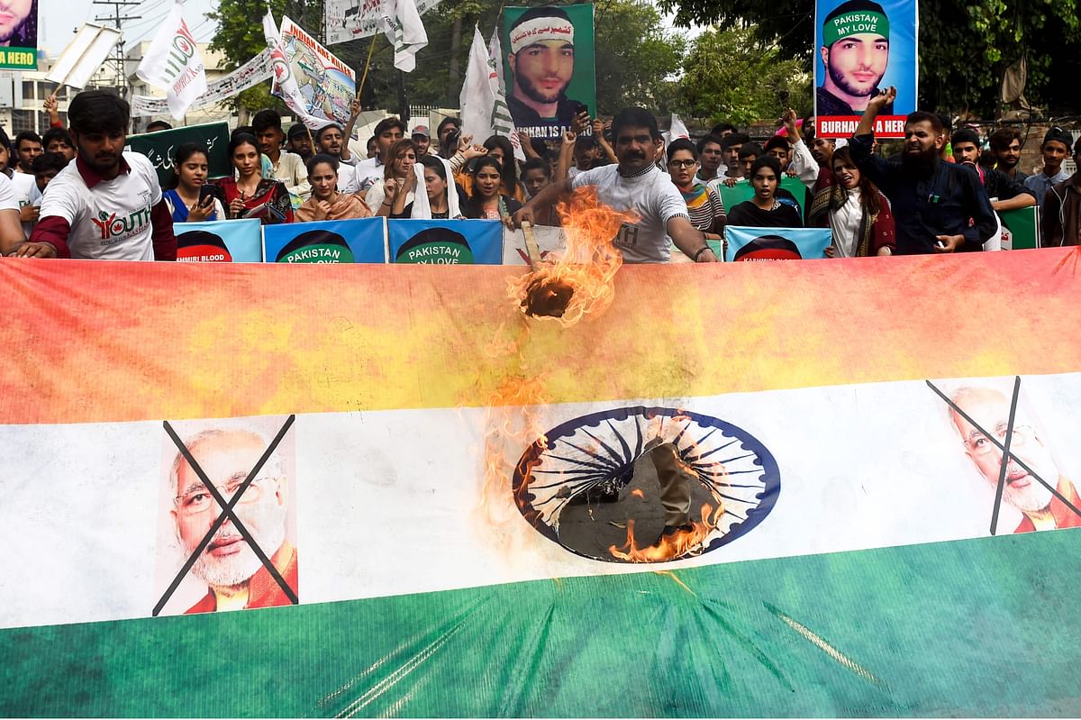 Pakistani activists of Youth Forum for Kashmir burn an Indian flag as they hold placards featuring images of slain Indian Kashmiri rebel leader Burhan Wani during a rally for the leader death anniversary, in Lahore on 8 July, 2019. Photo: AFP
