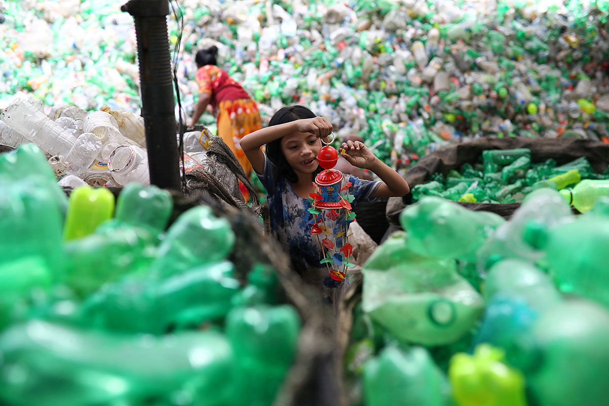A girl plays with a toy found in a plastic recycling factory in Dhaka, Bangladesh, 8 July, 2019. Photo: Reuters