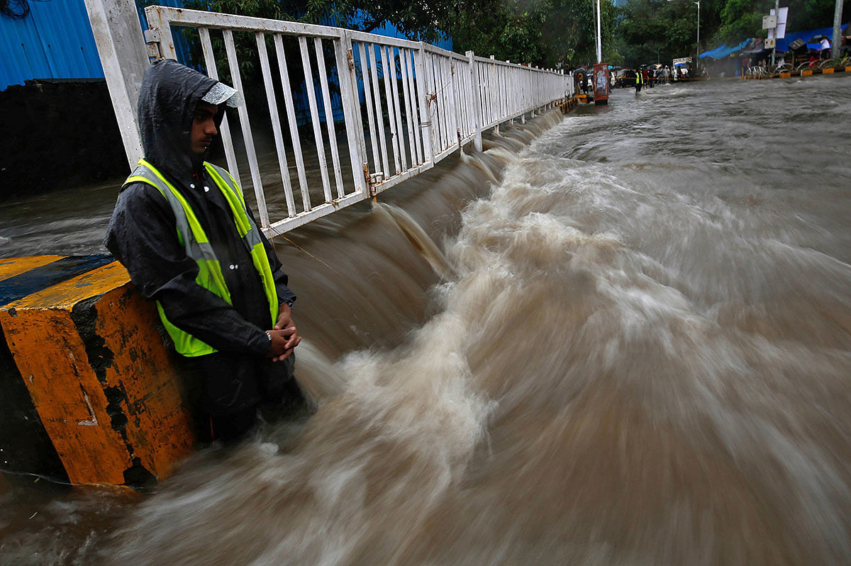 A volunteer stands guard next to a railing to prevent commuters from crossing a water-logged street after heavy rains in Mumbai, India, 8 July, 2019. Photo: Reuters