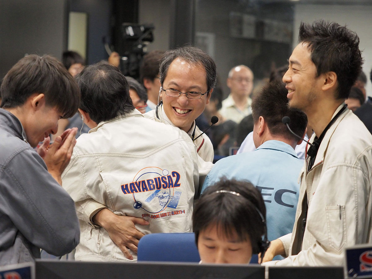 his handout photograph taken and released by the Institute of Space and Astronautical Science (ISAS) of Japan Aerospace Exploration Agency (JAXA) on 11 2019 shows researchers and employees celebrating after receiving confirmation of Hayabusa2`s touchdown on the asteroid Ryugu, at the mission control room in Sagamihara city, Kanagawa prefecture. Photo: AFP