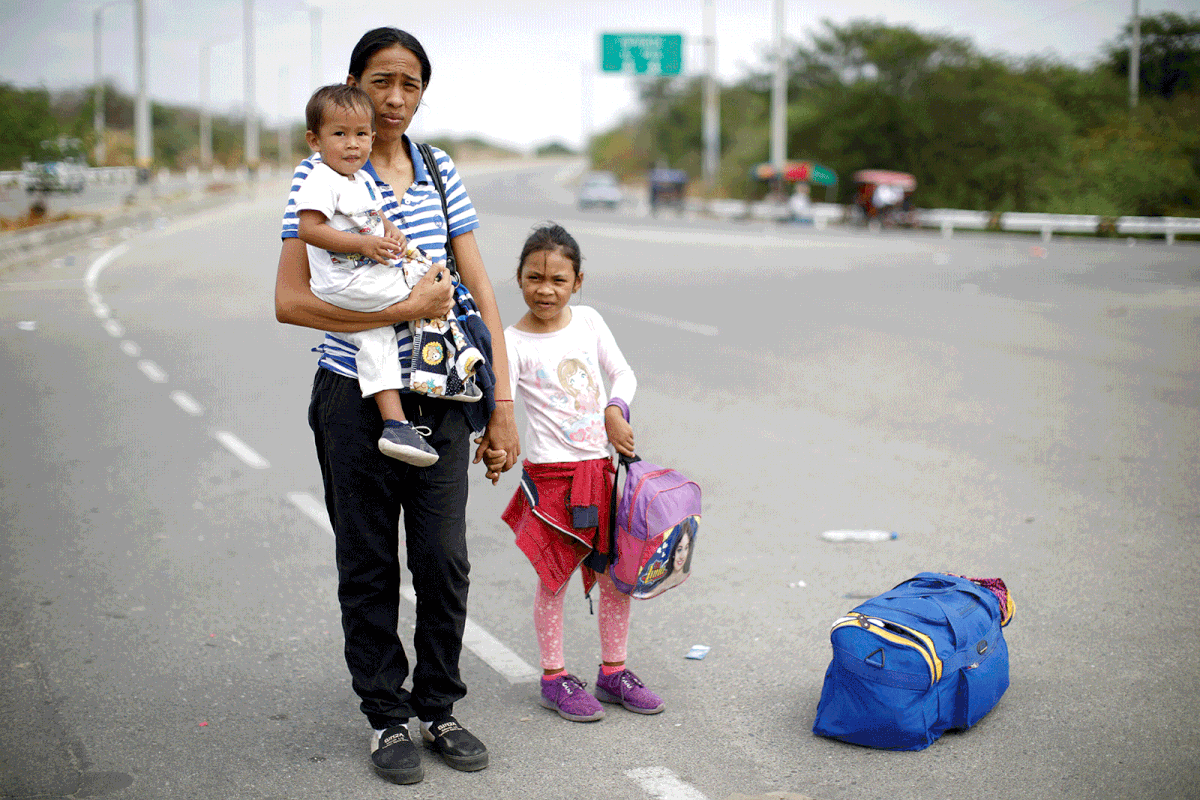 Venezuelan migrant Erika Quevedo, 28, poses for a picture with her children Osmariel, 6, and Gabriel, 1, as they wait for transport to continue their journey, after they processed their documents at the Ecuadorian-Peruvian border service center, on the outskirts of Tumbes, Peru, 17 June 2019. Photo: Reuters